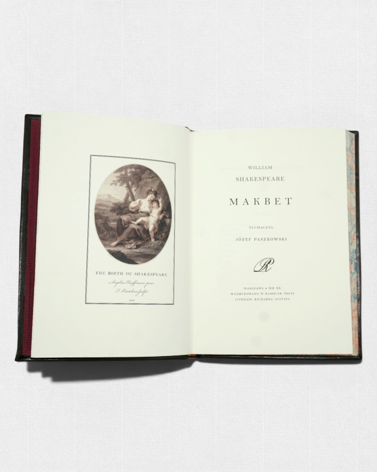 Otwarta książka „Makbet” Williama Shakespeare’a; po lewej stronie ilustracja „The Birth of Shakespeare”, po prawej karta tytułowa z nazwiskiem autora, tytułem i informacją o tłumaczu Józefie Paszkowskim.