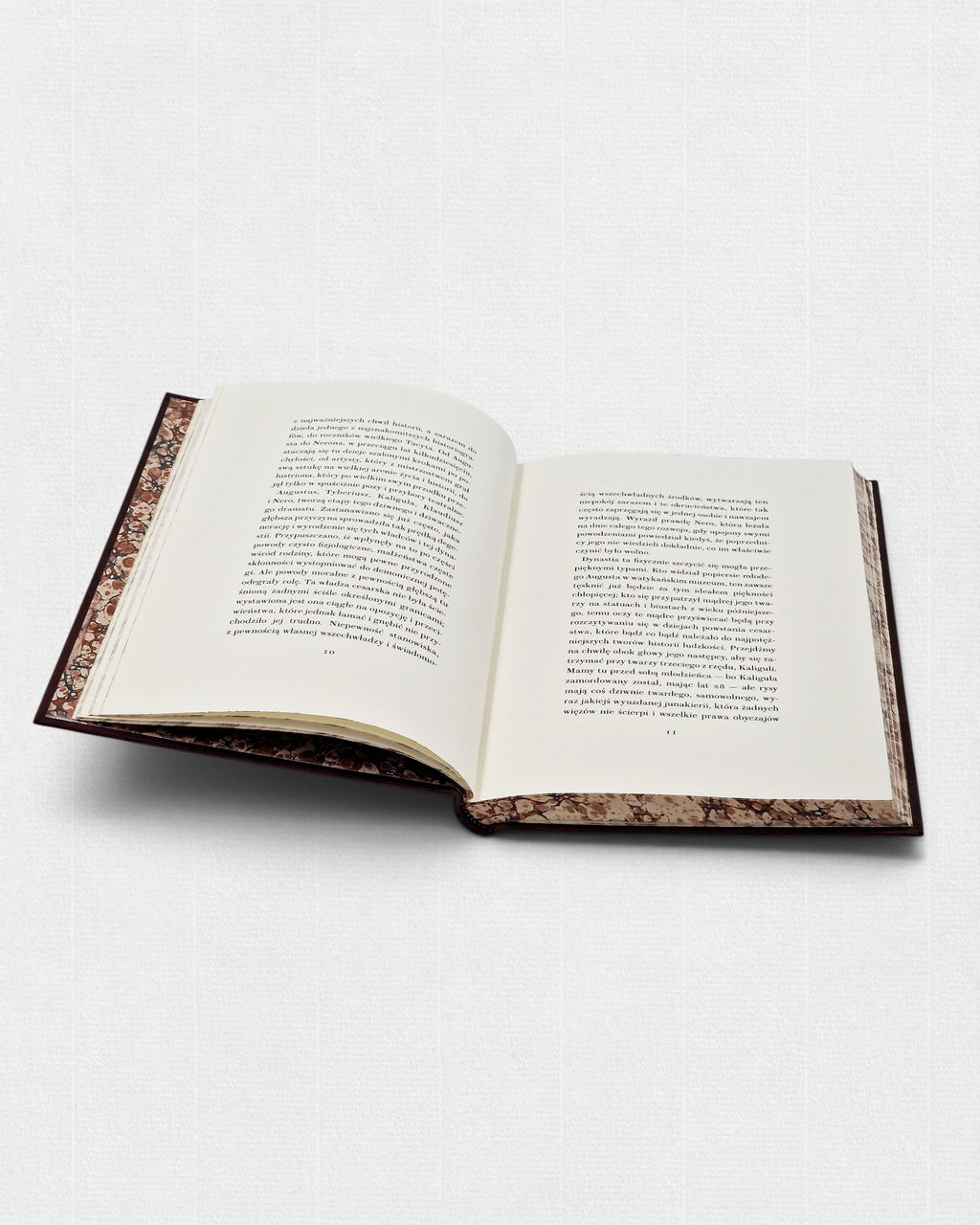Rozkładówka kolekcjonerskiego wydania „Cesarza Tyberiusza” Kazimierza Morawskiego przygotowanego przez Rambler Press. Widoczny skład wykonany krojem Brunel Text Roman No 2, szerokie marginesy, papier bawełniany Fabriano Tiepolo oraz marmoryzowane wyklejki inspirowane klasyczną europejską sztuką książki.