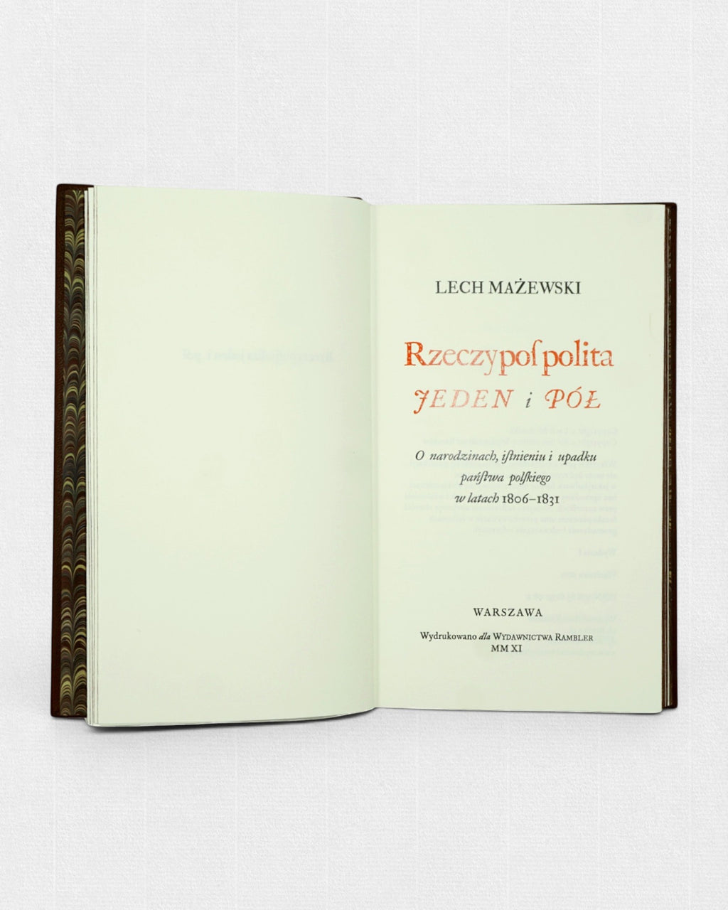Otwarte kolekcjonerskie wydanie książki „Rzeczpospolita jeden i pół” Lecha Mażewskiego przygotowane przez Rambler Press. Widoczna karta tytułowa z klasycznym składem typograficznym wykonanym krojem Williams Caslon oraz marmurkowe wyklejki inspirowane dawną sztuką książki i tradycją edytorstwa bibliofilskiego.