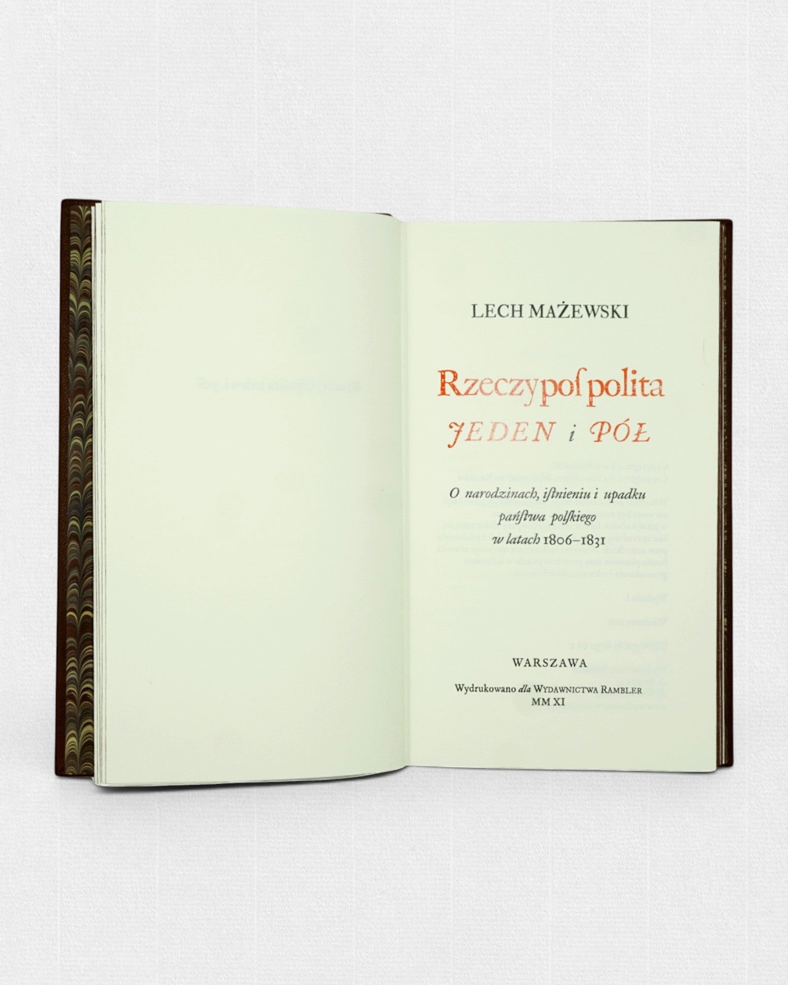 Otwarte kolekcjonerskie wydanie książki „Rzeczpospolita jeden i pół” Lecha Mażewskiego przygotowane przez Rambler Press. Widoczna karta tytułowa z klasycznym składem typograficznym wykonanym krojem Williams Caslon oraz marmurkowe wyklejki inspirowane dawną sztuką książki i tradycją edytorstwa bibliofilskiego.