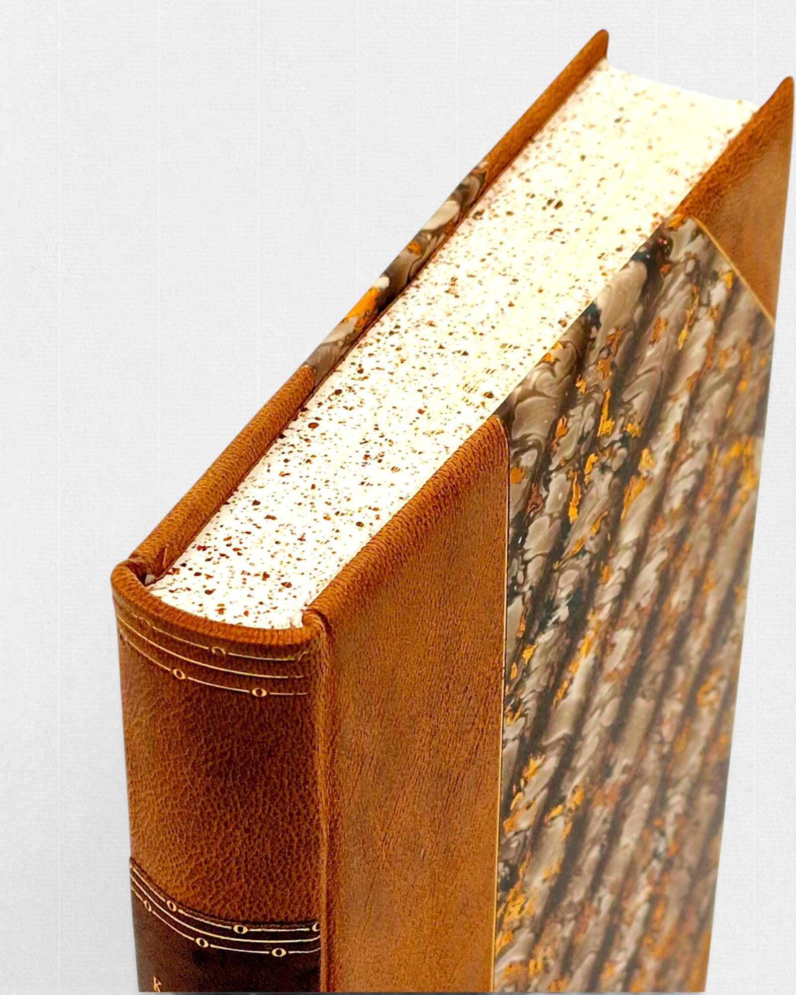 Detal ręcznie oprawionego kolekcjonerskiego wydania „Kandyda” Woltera — skórzana oprawa, papier marmurkowy i barwione brzegi bloku książki w edycji bibliofilskiej Rambler Press.